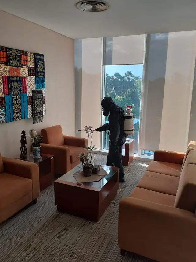 Petugas menyemprot cairan disinfektan di kantor BI NTT. (Liputan6.com/Ola Keda)