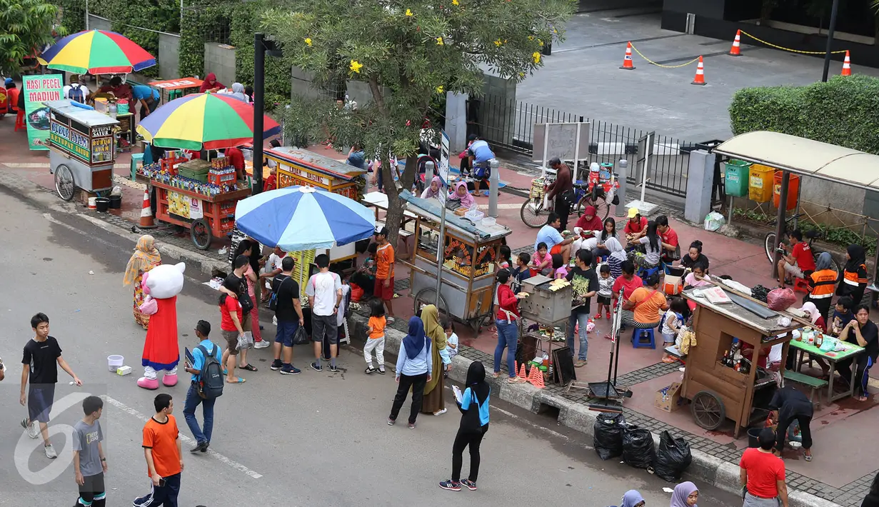 Pedagang kopi sepeda keliling melayani pembelinya di kawasan car free day, Jakarta, Minggu (14/5). Meskipun telah dilarang, namun kurangnya pengawasan menyebabkan banyak PKL yang kembali berjualan di kawasan tersebut. (Liputan6.com/Immanuel Antonius)