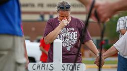 Penduduk Santa Fe, Lori Simmons menangis saat mengheningkan cipta di depan SMA Santa Fe di Texas, AS, Senin (21/5). Korban tewas penembakan Texas terdiri dari delapan siswa dan dua guru. (Steve Gonzales/Houston Chronicle via AP)