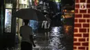 Warga melintasi genangan banjir di kawasan Kemang, Jakarta, Selasa (4/10/2022). Jalan Kemang Utara IX tak bisa dilalui oleh kendaraan. Banjir menggenangi kawasan Pasar Kambing dan sejumlah rumah penduduk. (Liputan6.com/Faizal Fanani)
