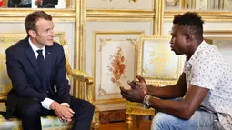 Presiden Prancis Emmanuel Macron (kiri) berbincang dengan Mamoudou Gassama di Istana Elysee, Paris, Prancis, Senin (29/5). Berkat kepahlawanannya, Macron menghadiahinya medali dan menawarinya kewarganegaraan Prancis. (AP Photo/Thibault Camus, Pool)