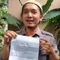 Muhammad Sabil Fadhillah menunjukkan surat pemberhentian dari SMK Telkom Cirebon imbas kritiknya di kolom komentar akun IG Ridwan Kamil. Foto (Liputan6.com / Panji Prayitno)