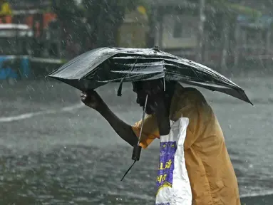 Seorang pejalan kaki menyeberangi jalan yang tergenang air setelah hujan lebat di Chennai, kawasan Teluk Benggala, Timur India pada 4 Desember 2023. (R. Satish BABU/AFP)