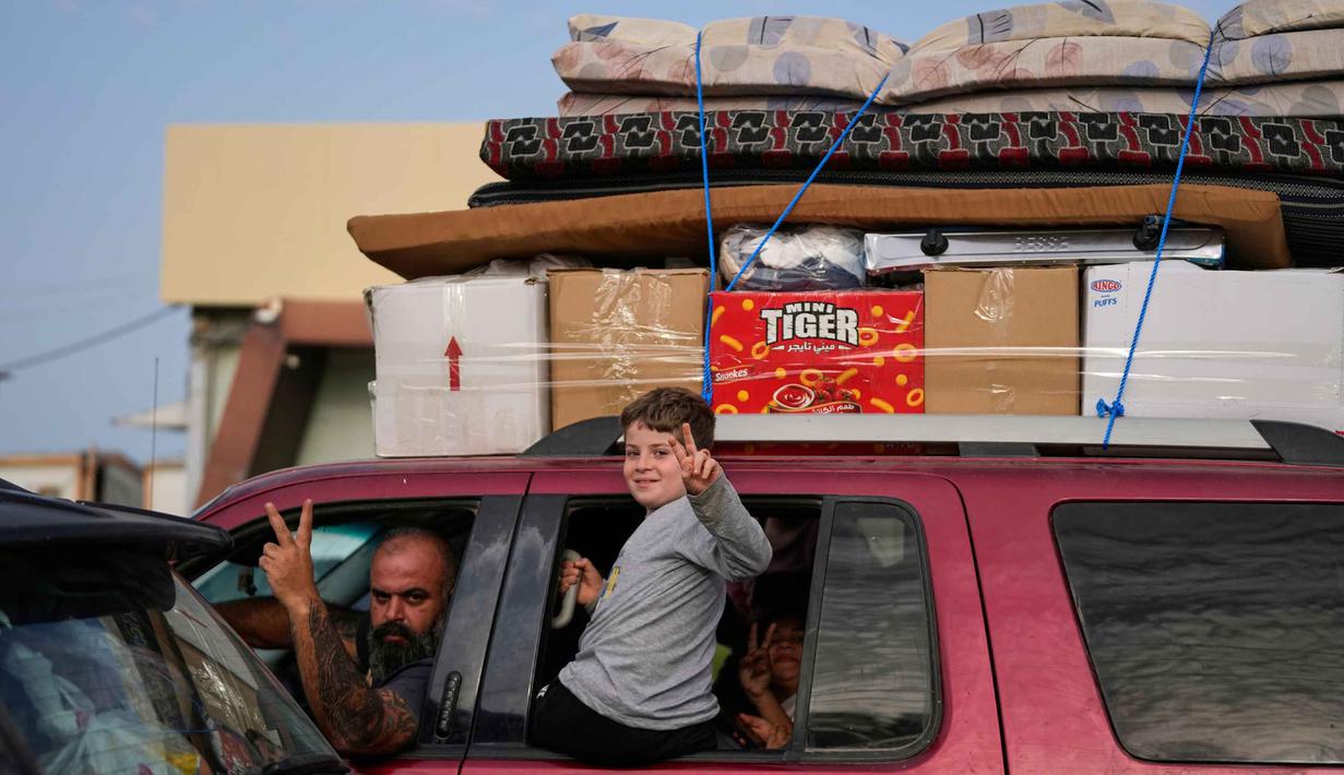 Para pengungsi mengacungkan tanda kemenangan di Qasmiyeh dekat kota Tyre, Lebanon Selatan, saat mereka kembali ke desa mereka setelah gencatan senjata antara Hizbullah dan Israel, Jumat 17 April 2026. Warga Lebanon mulai bergerak kembali ke rumah dan desa mereka, terutama di wilayah selatan, menyusul diumumkannya kesepakatan gencatan senjata sementara selama 10 hari antara Israel dan Hizbullah. (AP Photo/Mohammed Zaatari)