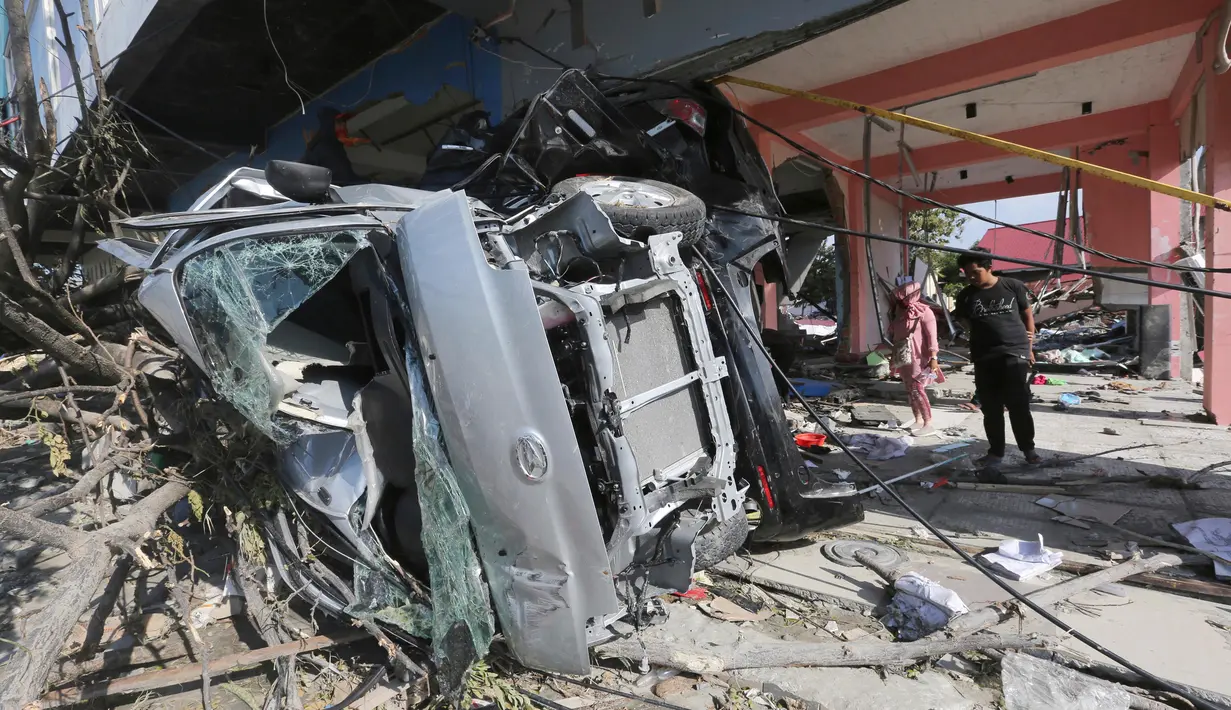 Warga mengecek rumah dan mobil yang hancur setelah gempa dan tsunami di pantai Talise di Palu, Sulawesi Tengah (1/10). Gempa berkekuatan 7,4 Magnitudo disusul tsunami melanda Palu dan Donggala pada 28 September 2018. (AP Photo/Tatan Syuflana)