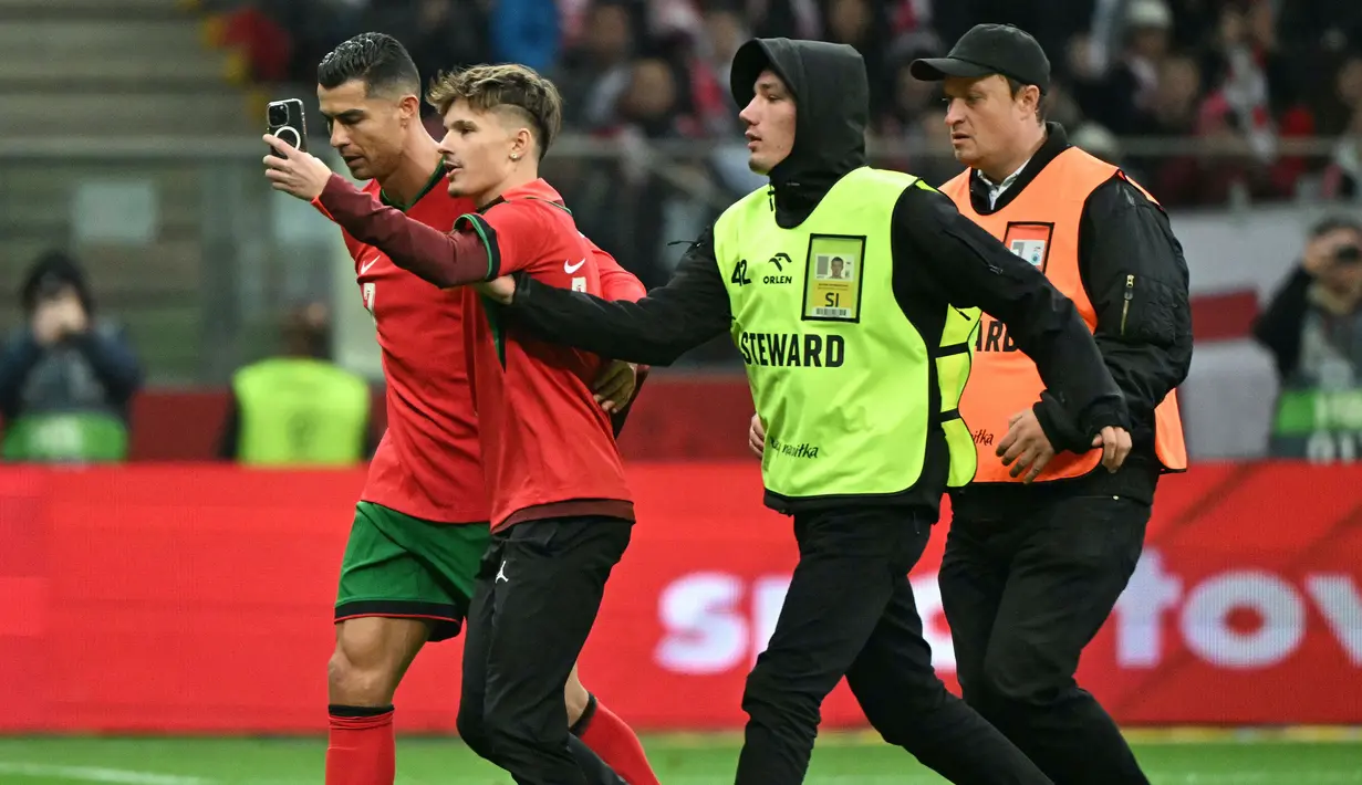 Pihak pengamanan menangkap seorang penyusup lapangan saat berusaha melakukan swafoto dengan pemain Portugal, Cristiano Ronaldo ketika laga lanjutan EUFA Nations League Polandia di National Stadium, Warsawa, Polandia, Minggu (13/10/2024) WIB. (AFP/Sergei Gapon)