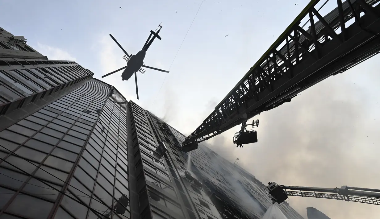 Sebuah helikopter membawa air menyiramkan air ke gedung kantor yang terbakar di Dhaka (28/3). Kebakaran besar melanda gedung perkantoran yang menewaskan sedikitnya lima orang dan lainnya masih terperangkap dalam gedung yang terbakar tersebut. (AFP/Munir Uzzaman)