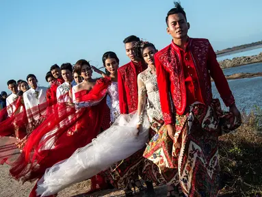 Model mengenakan busana kebaya bertema merah putih saat fashion show di tanggul Lapindo Porong, Sidoarjo, Jawa Timur, Selasa (13/8/2019). Peragaan busana yang menampilkan busana kebaya tersebut untuk memeriahkan HUT ke-74 kemerdekaan RI. (Photo by JUNI KRISWANTO / AFP)
