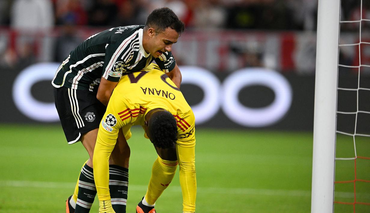 Bek Manchester United, Sergio Reguilon berusaha mengangkat dan menyemangati Andre Onana setelah kebobolan gol pertama melalui tendangan gelandang Bayern Munchen, Leroy Sane pada laga matchday pertama Grup A Liga Champions 2023/2024 di Allianz Arena, Munich, Kamis (21/9/2023) dini hari WIB. (AFP/Tobias Schwarz)