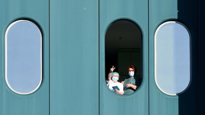 Petugas medis menunjukkan isyarat kemenangan dari jendela Rumah Sakit Dubrava, Kroasia, 15 Maret 2020. Pandemi virus corona COVID-19 membuat Kroasia menangguhkan semua layanan transportasi umum selama 30 hari ke depan. (Photo by Denis LOVROVIC/AFP)