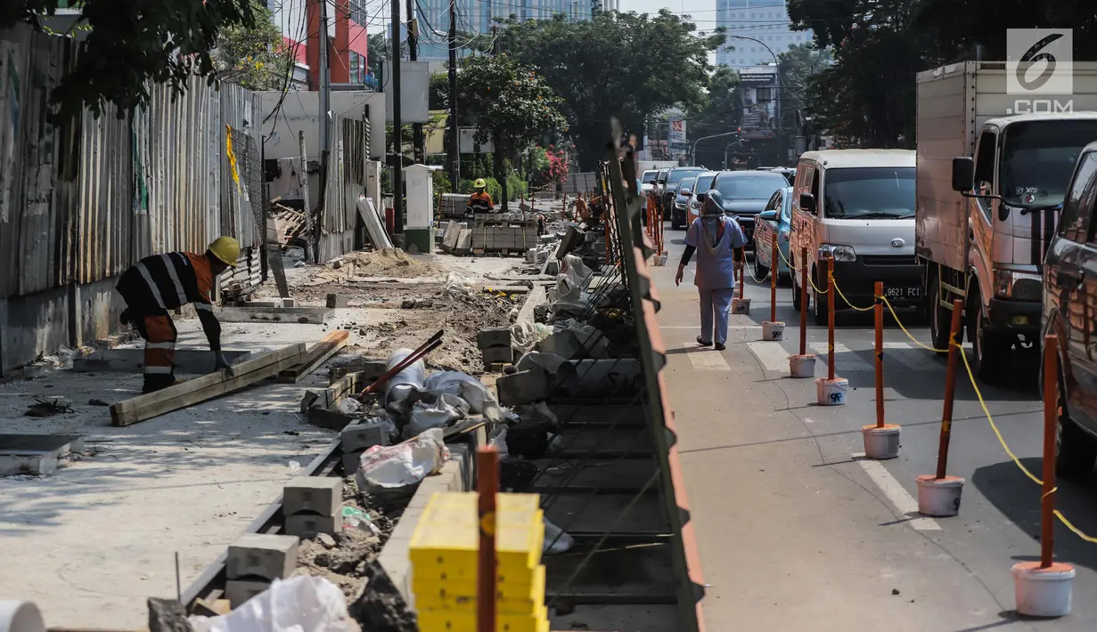 Kendaraan melintas di samping proyek revitaslisasi trotoar di kawasan Cikini, Jakarta, Senin (1/7/2019). Revitalisasi trotoar di kawasan Cikini hingga Kramat ditargetkan rampung pada Desember 2019. (Liputan6.com/Faizal Fanani)