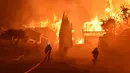 Petugas memadamkan api di sebuah rumah di Ventura, California, AS (5/12). Sekitar penghuni 7.786 rumah di Ventura dan Santa Paula mendapat mandat evakuasi wajib dari dinas pemadam kebakaran lokal. (Ryan Cullom / Ventura County Fire Department via AP)