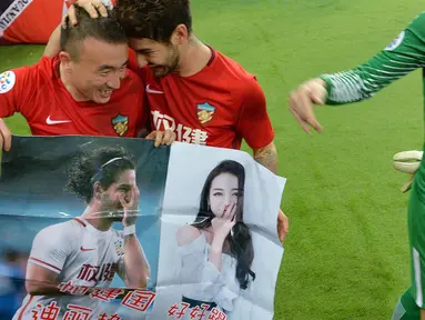 Penyerang Tianjin Quanjian, Alexandre Pato dan rekannya membawa poster aktris Dilraba Dilmurat usai pertandingan melawan South Hyundai Jeonbuk di Liga Champions AFC  di Tianjin (14/3). Poster tersebut tidak diketahui siapa yang buat. (AFP Photo)