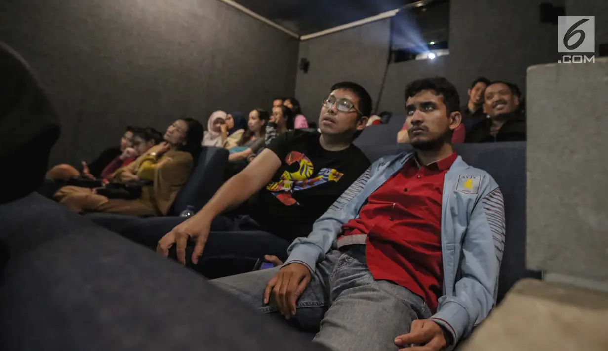 Relawan bisik menjelaskan alur cerita kepada penyandang tunanetra saat menyaksikan film di Bioskop Bisik di Pavilliun 28, Jakarta, Minggu (14/1). Hal ini membuat menonton bioskop bukan menjadi hal mustahil lagi bagi tunanetra. (Liputan6.com/Faizal Fanani)