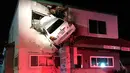 Sebuah mobil tertancap di bangunan lantai dua klinik dokter gigi di Santa Ana, California, Minggu (14/1). Mobil itu melaju kencang hingga terbang ke udara dan menembus bangunan lantai dua hingga melukai dua orang. (Orange County Fire Authority via AP)