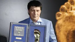 Kiper Rusia Rinat Dasaev berpose dengan trofi Golden Foot miliknya, Monaco, Senin (21/9/2015). Golden Foot 2015 diraih lima orang yaitu Rinat Dasaev, Daniel Passarella, Gheorghe Hagi,  Trezeguet dan Eto'o. (AFP Photo/Valery Hache)
