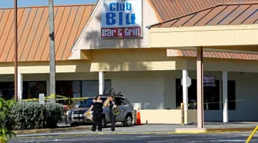 Petugas polisi berjalan di tempat parkir Club Blu setelah insiden penembakan di Fort Myers, Florida, Senin (25/7). Dua orang tewas dalam serangan penembakan di klub malam tersebut yang dilaporkan sebagai tempat pesta untuk remaja. (REUTERS/Joe Skipper)