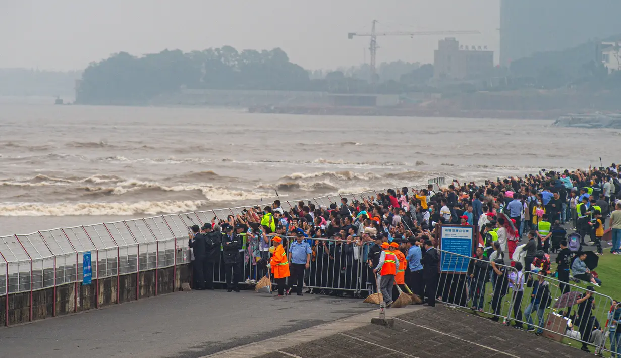 Warga menyaksikan gelombang pasang Sungai Qiantang dari pinggir sungai di Hangzhou, Zhejiang, China, 4 Oktober 2020. Gelombang pasang Sungai Qiantang yang terkenal dengan tinggi dan kecepatannya terjadi bertepatan dengan libur Hari Nasional dan Festival Pertengahan Musim Gugur. (Xinhua/Jiang Han)
