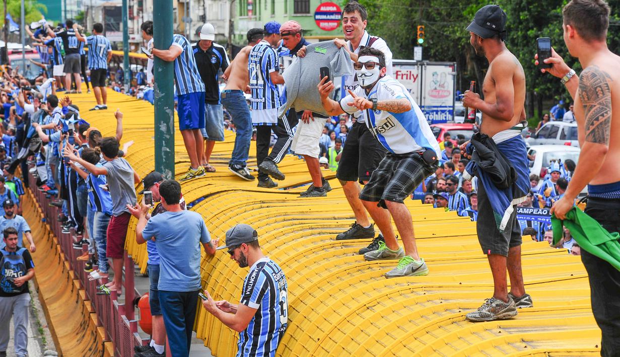 Suporter merayakan keberhasilan Gremio meraih juara Copa Libertadores di Porto Alegre, Brasil, Kamis (30/11/2017). Gremio menjadi juara Copa Libertadores setelah mengalahkan Lanus dengan skor agregat 3-1. (AFP/Itamar Aguiar)
