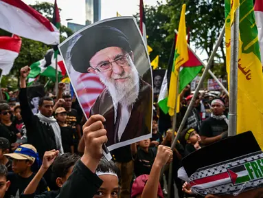 Seorang anak laki-laki memegang plakat bergambar pemimpin tertinggi Iran, Ayatollah Ali Khamenei yang gugur dalam serangan Amerika Serikat dan Israel pada akhir Februari lalu, selama berunjuk rasa memperingati Hari Al-Quds, di Surabaya, Jawa Timur, Jumat (13/3/2026). Ratusan orang turun ke jalan menggelar aksi unjuk rasa memperingati Hari Al-Quds Internasional. (Juni KRISWANTO/AFP)
