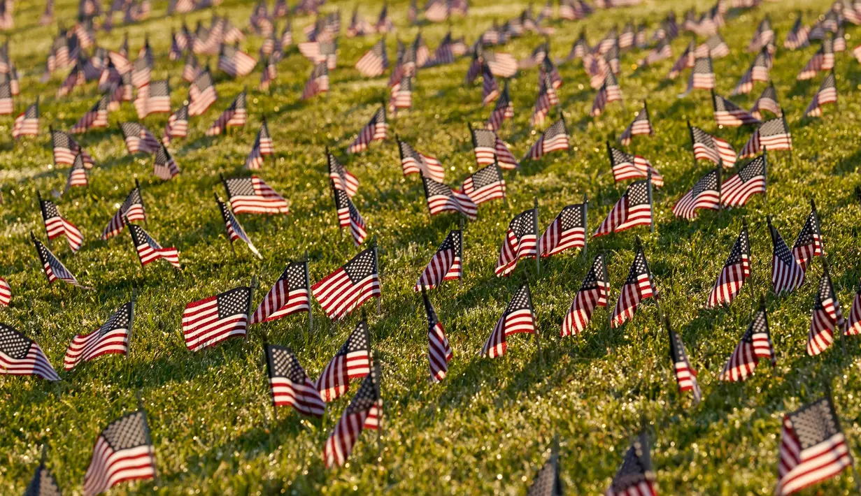 Aktivis dari COVID Memorial Project meletakkan ribuan bendera Amerika berukuran kecil di di halaman National Mall di Washington, Selasa (22/9/2020). Ribuan bendera itu menandai 200 ribu nyawa yang hilang akibat virus corona Covid-19 di Amerika Serikat. (AP Photo/J. Scott Applewhite)