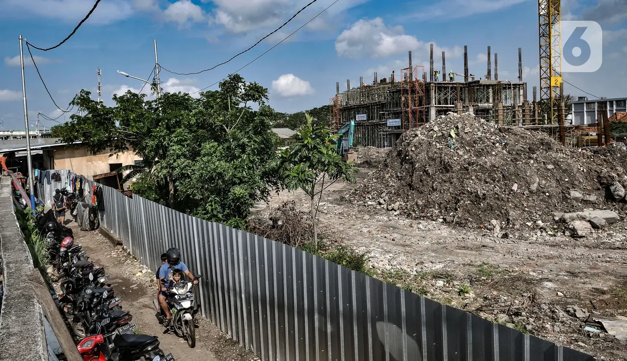 Warga melintas di dekat proyek Kampung Susun Akuarium, Penjaringan, Jakarta, Kamis (11/3/2021). Menurut Ketua RT Kampung Akuarium, Topas, mengungkapkan dua dari lima blok Kampung Susun Akuarium ditargetkan rampung pada Agustus 2021. (merdeka.com/Iqbal S. Nugroho)