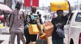 Seorang perempuan membawa jeriken saat berjalan melewati mobil yang mengantre untuk membeli bahan bakar di sebuah pompa bensin di Lagos, Nigeria Selasa, 30 April 2024. (AP Photo/Sunday Alamba)