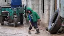 Seorang bocah memegang alat pembersih lumpur di kamp pengungsi Bab Al-Salam, dekat perbatasan Suriah-Turki, Provinsi Aleppo Utara, Senin (26/12). Di pengungsian ini tercatat sekitar ribuan warga yang telah lama hidup di tenda. (REUTERS/Khalil Ashawi)
