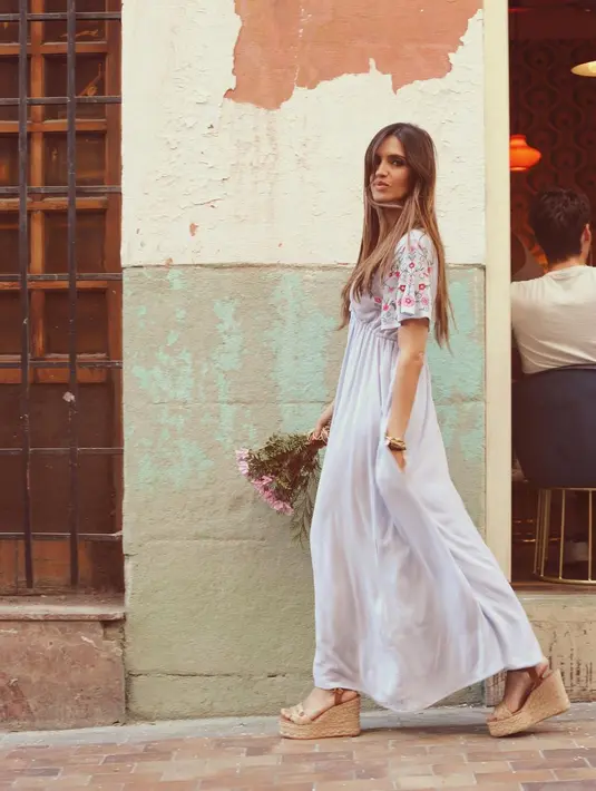 Sambil membawa bunga, Sara Carbonero tampil dengan gaya romantis mengenakan gaun berwarna putih keabu-abuan. Motif bunga di bagian lengan memberi kesan feminin. (instagram/saracarbonero)