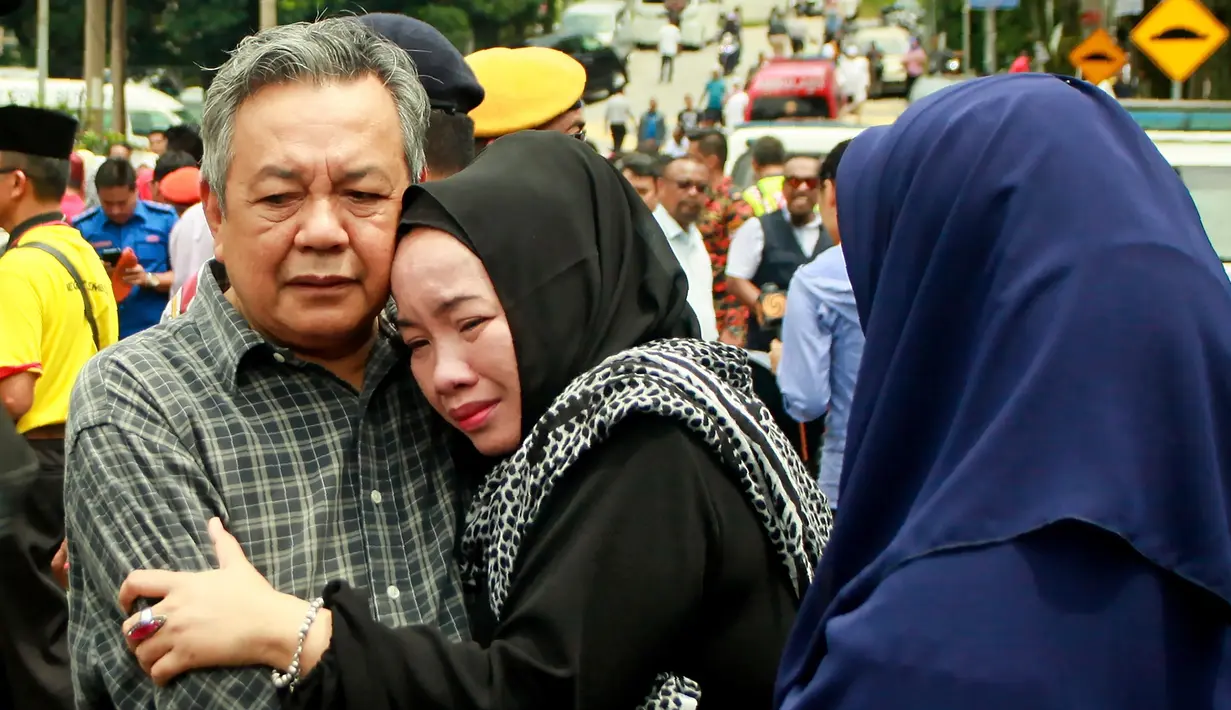 Suasana haru yang menyelimuti kedua orang tua dari korban kebakaran sekolah agama Darul Quran Ittifaqiyah di Kuala Lumpur, Malaysia (14/9). Kebakaran tersebut terjadi pada Kamis dini hari waktu setempat. (AFP Photo/Sadiq Asyraf)