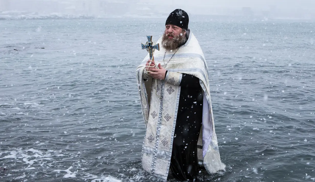 Pastor Rusia Sergius memberkati air laut sebelum mandi Epiphany di Kholmsk, 90 kilometer barat Yuzhno-Sakhalinsk, Pulau Sakhalin di Timur Jauh Rusia, Jumat (19/1). Air yang diberkati dipercaya bisa menyembuhkan penyakit. (AP Photo/Sergey Krasnoukhov)