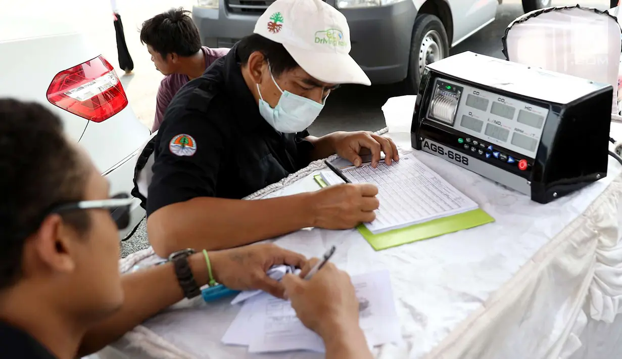 Petugas sudin lingkungan hidup mengisi form uji emisi gas buang kendaraan di kawasan Senayan, Jakarta, Rabu (18/7). Uji emisi gratis dilakukan untuk menekan tingkat pencemaran udara akibat gas buang kendaraan. (Liputan6.com/Immanuel Antonius)