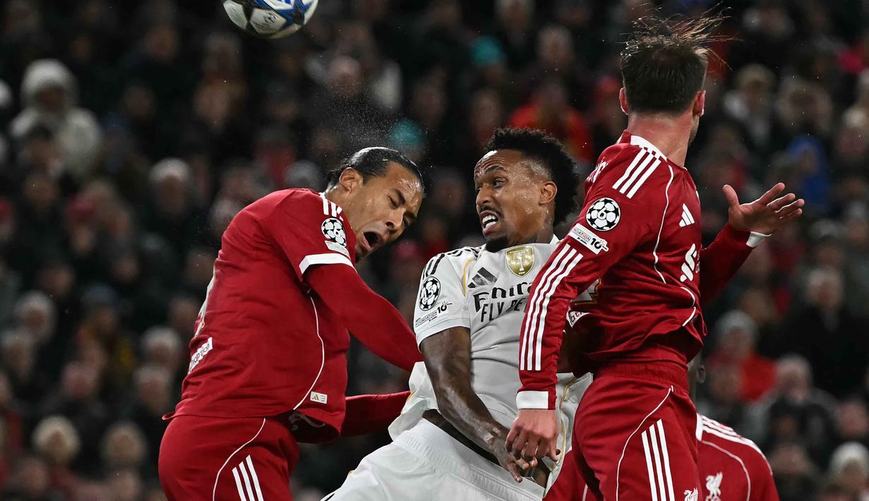 Bek Real Madrid asal Brasil, Eder Militao (tengah) berebut bola dengan bek Liverpool asal Belanda, Virgil van Dijk (kiri) dalam pertandingan pekan keempat Liga Champions 2025-2026 di Stadion Anfield, Inggris, pada Selasa 4 November 2025 waktu setempat atau Rabu (5/11/2025) dini hari WIB. Tampil di bawah tekanan, Real Madrid terus mencoba mengambil inisiatif serangan. (Paul ELLIS/AFP)
