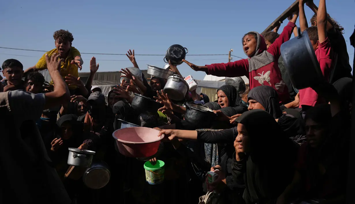 Warga Palestina menunggu bantuan gula dan beras di dapur umum di Khan Younis, Jalur Gaza selatan, Jumat, 31 Oktober 2025. Namun, sering kali, makanan yang tersedia seperti sup, nasi, atau lentil rebus, sangat terbatas dan banyak yang pulang dengan tangan kosong karena kehabisan. (AP Photo/Abdel Kareem Hana)
