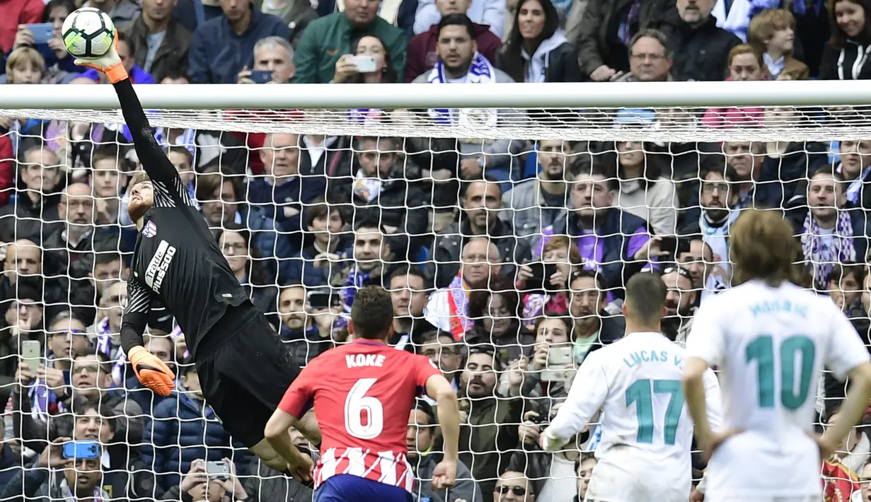 Kiper Atletico Madrid, Jan Oblak, mengamankan gawangnya dari tendangan pemain Real Madrid pada laga La Liga Spanyol di Stadion Santiago Bernabeu, Madrid, Minggu (8/4/2018). Kedua klub bermain imbang 1-1. (AFP/Javier Soriano)