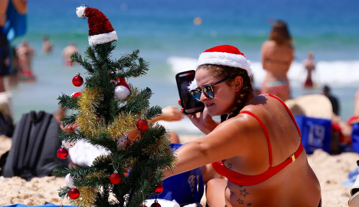 Wisatawan merapihkan pohon natal saat ia merayakan hari Natal di Bondi Beach Sydney pada Hari Natal di Australia, (25/12). (REUTERS/David Gray)