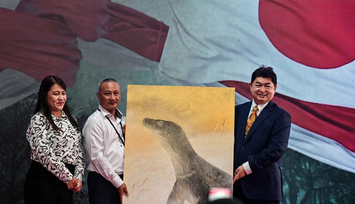 Direktur iZoo Jepang, Tuyoshi Shirawa (kanan); Direktur Operasi dan Urusan Umum Kebun Binatang Surabaya, Nurika Widyasa (kiri); dan Direktur Keuangan dan Sumber Daya Manusia (SDM) Kebun Binatang Surabaya, Moch. Nahroni berpose dengan lukisan komodo setelah menandatangani nota kesepahaman mengenai kerja sama dalam perlindungan dan konservasi satwa liar antara Indonesia dan Jepang di Kebun Binatang Surabaya, Jawa Timur, pada Rabu 29 April 2026. (JUNI KRISWANTO/AFP)