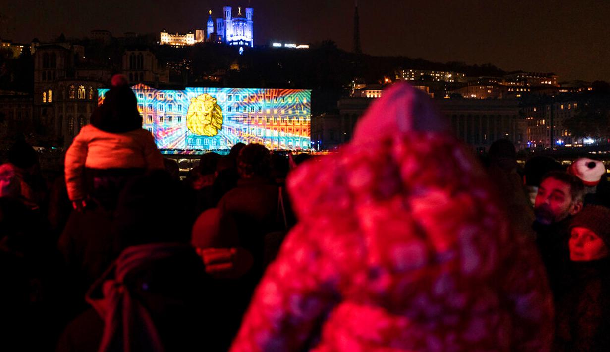 Orang-orang menghadiri pertunjukan cahaya malam di Lyon, Prancis, 8 Desember 2022. Jutaan orang diperkirakan akan menyaksikan acara Festival Cahaya selama empat hari di kota tersebut. (AP Photo/Laurent Cipriani)