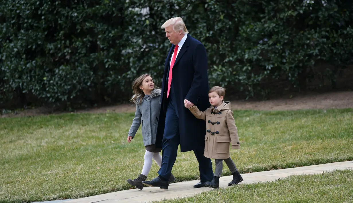 Presiden AS, Donald Trump berjalan bersama cucunya, Arabella dan Joseph Kushner menuju Marine One saat berangkat ke Carolina Selatan dari Gedung Putih, di Washington, AS, (17/2). (AFP Photo/ Mandel Ngan)