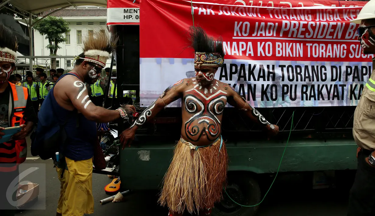 Seorang demonstran mengecat tubuhnya sebelum menggelar unjuk rasa di depan Kementerian Energi dan Sumber Daya Mineral (ESDM) Jakarta, Selasa (7/3). (Liputan6.com/Johan Tallo)