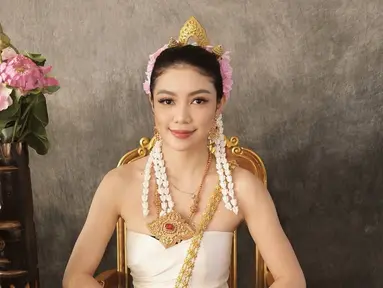 Dalam foto yang diunggah, Regina Phoenix menunjukkan pesona luar biasa dengan baju adat Thailand, Chut Thai, yang memperlihatkan keindahan budaya tradisional negeri gajah putih. Suasana yang elegan dan berkelas terlihat saat Regina duduk di kursi berlapis emas dengan latar belakang yang klasik. Senyum lembutnya menambah daya tarik, membuat setiap orang yang melihatnya terpesona. (Liputan6.com/IG/@reginaaphx)
