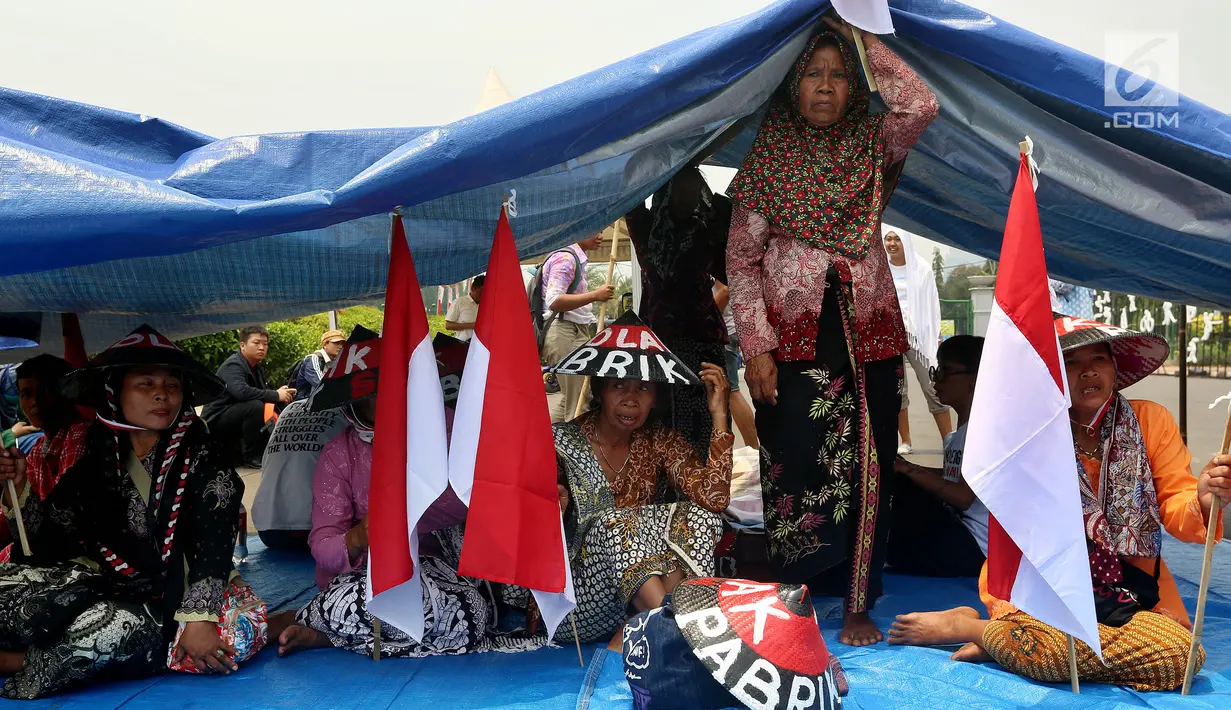 Petani Pegunungan Kendeng melakukan aksi teatrikal dan mendirikan tenda di depan Istana Merdeka, Jakarta, Senin (4/9). Sebanyak tujuh bendera Merah Putih dikibarkan di setiap tiang tenda yang didirikan di seberang Istana. (Liputan6.com/Johan Tallo)