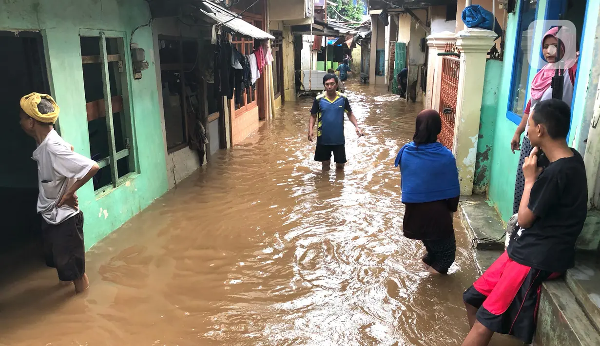 Warga beraktivitas di tengah banjir yang merendam kawasan Kebon Pala, Jakarta Timur, Selasa (25/2/2020). Akibat banjir yang tak kunjung surut, aktivitas warga di kawasan tersebut menjadi terganggu, terlebih dengan adanya pemadaman listrik. (Liputan6.com/Immanuel Antonius)