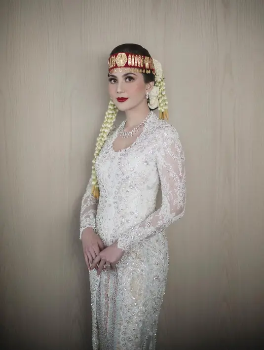 Memukaunya penampilan Jessica Mila di acara pernikahan adat Bataknya mengenakan kebaya putih. Kebaya putih penuh payet dipadu dengan kain adat serasi dan hiasan kepala merah yang sangat ikonis untuk pengantin perempuan. [Foto: Instagram/jscmila]