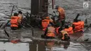 Sejumlah pasukan oranye berjibaku membersihkan sampah batang kayu dan bambu yang tersangkut di aliran sungai Ciliwung di kawasan Sudirman, Jakarta, Jumat (9/2). (Liputan6.com/Faizal Fanani)