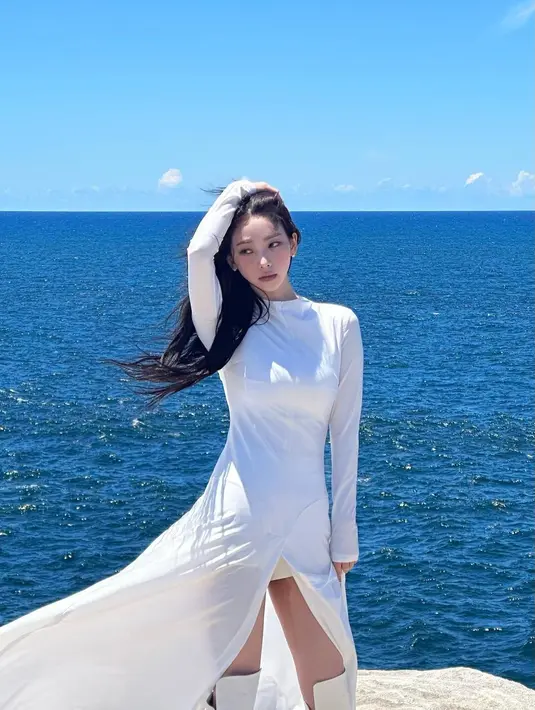 Karina aespa melakukan photoshoot di atas kapal dengan mengenakan outfit serba putih. Karina mengenakan dress lengan panjang yang super panjang menjuntai dengan high slit di bagian depan, dipadukan high boots yang juga berwarna putih. [Foto: Instagram/katarinabluu]