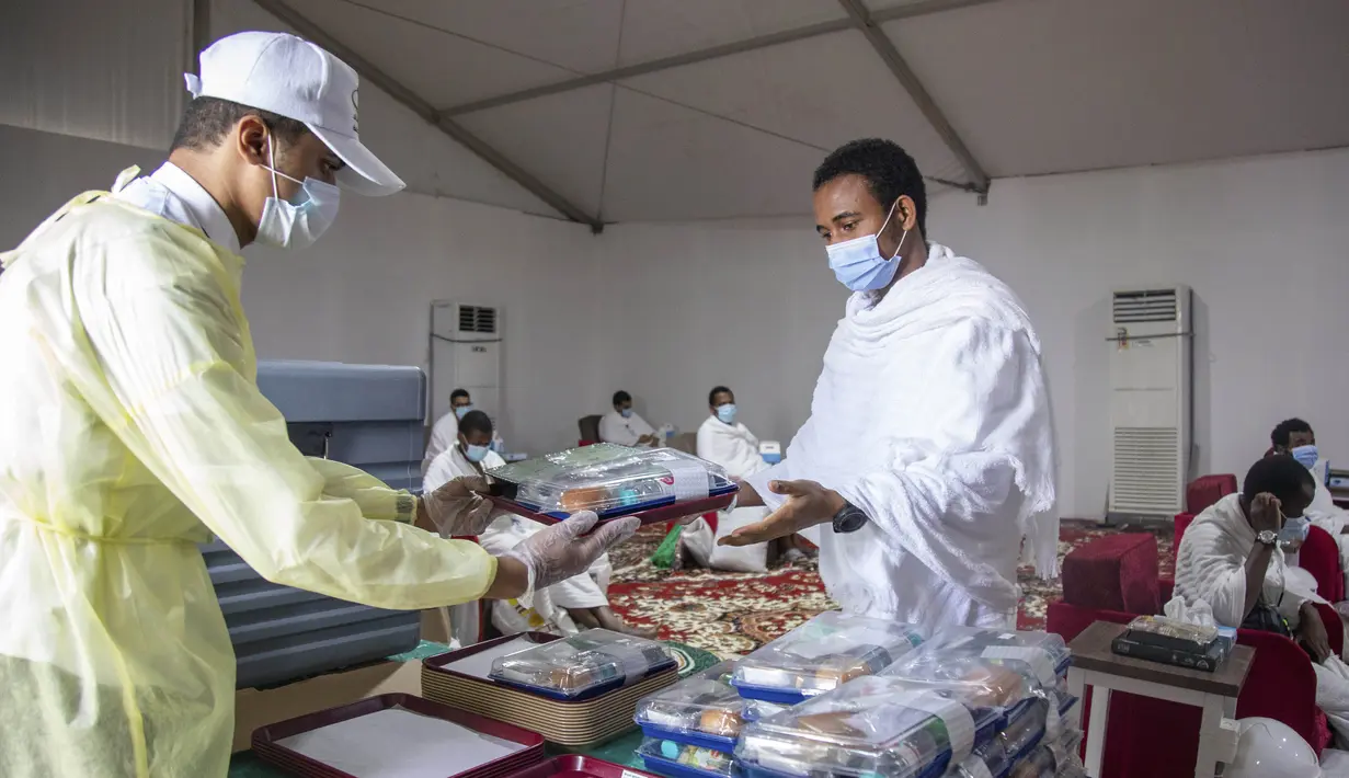 Jemaah mengambil makanan dalam kamp saat melaksanakan rangkaian ibadah haji di Kota Suci Makkah, Arab Saudi, Kamis (30/7/2020). Hanya sekitar seribu jemaah yang diizinkan untuk melakukan ibadah haji tahun ini karena pandemi COVID-19. (Saudi Ministry of Media via AP)