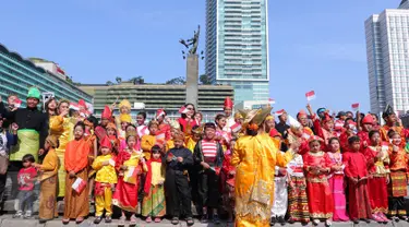 Sejumlah murid sekolah minggu Gereja Eban Haezer mengenakan baju adat sambil melambaikan bendera nasional di Bundaran HI Jakarta, Minggu (21/8). Menyanyikan lagu Indonesia Raya dan lagu daerah, mereka memperingati HUT RI ke 71. (Liputan6.com/Angga Yuniar)