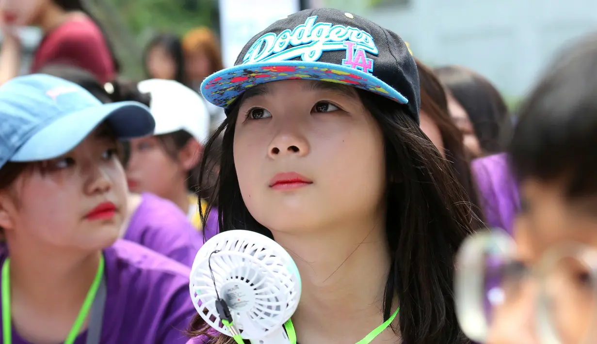 Seorang siswa memegang kipas portabel saat berunjuk rasa di Kedutaan Besar Jepang di Seoul, Korea Selatan, Rabu (1/8). Badan Meteorologi Korea Selatan mengeluarkan peringatan gelombang panas untuk Seoul dan kota-kota lainnya. (AP Photo/Ahn Young-joon)