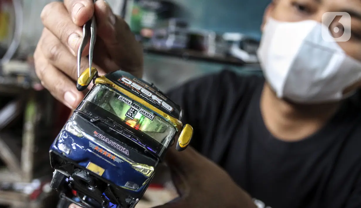 Perajin menyelesaikan pembuatan miniatur bus di Workshop Belang Bentong, Limo, Depok, Jawa Barat, Jumat (14/1/2022). Kerajinan miniatur bus berbahan baku akrilik dan resin tersebut dipasarkan ke berbagai daerah dengan harga Rp 700 ribu hingga Rp 1 juta per unit. (Liputan6.com/Johan Tallo)